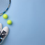Tennis racket and shoes on blue background, copy space